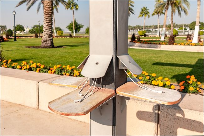 USB charging cables at a public charging station in a park.